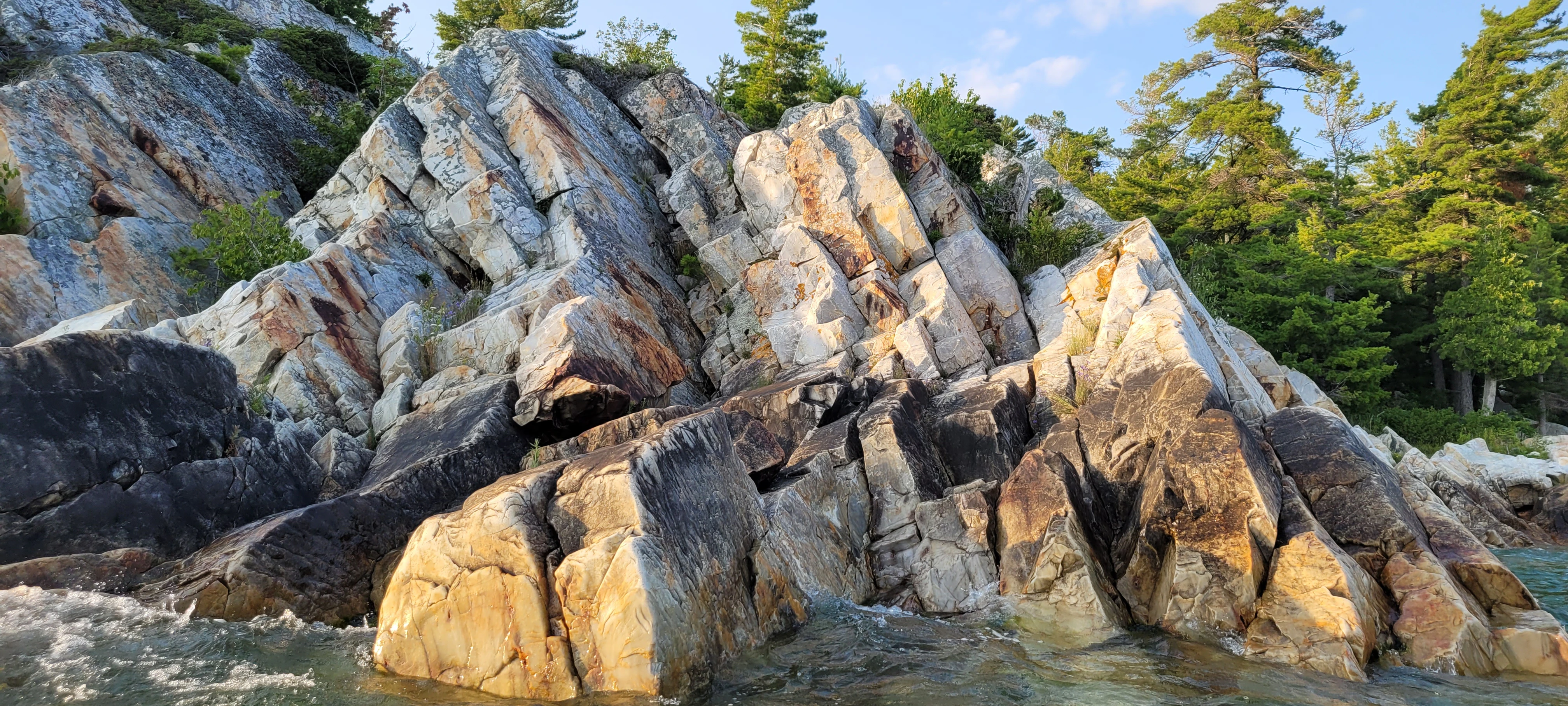 Sharp and block shaped white quartzite cliffs along the water's edge in the Killarney Bay in Ontario, Canada