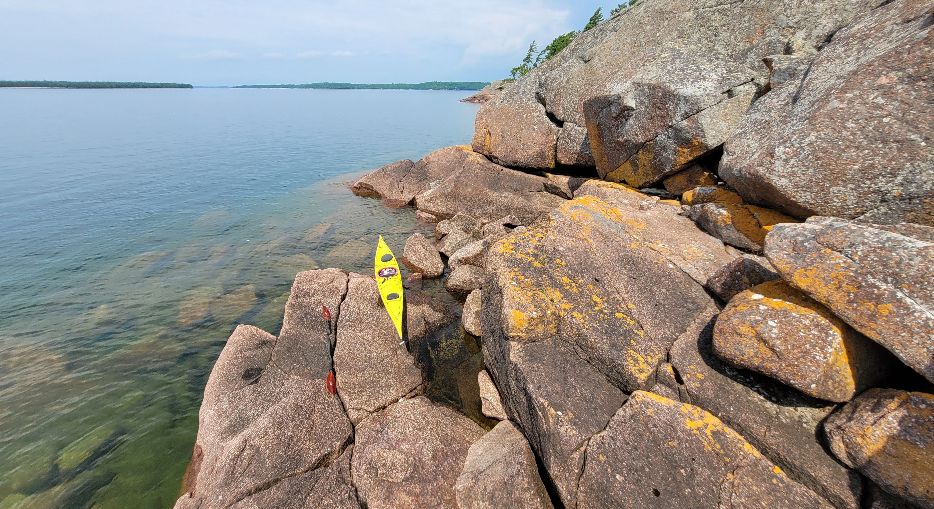 Western Shoreline of the Benjamind islands with red granite rock, white quartzite,
                trees and clear water