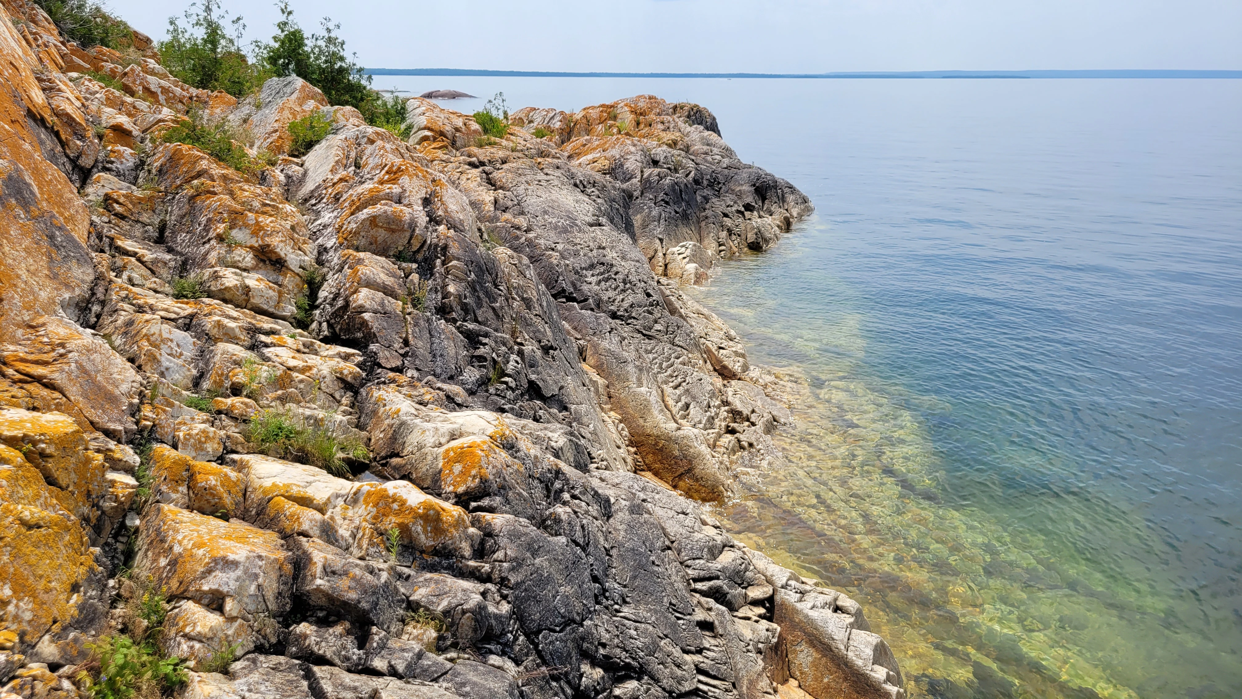 Western Shoreline of the Benjamind islands with red granite rock, white quartzite,
                trees and clear water