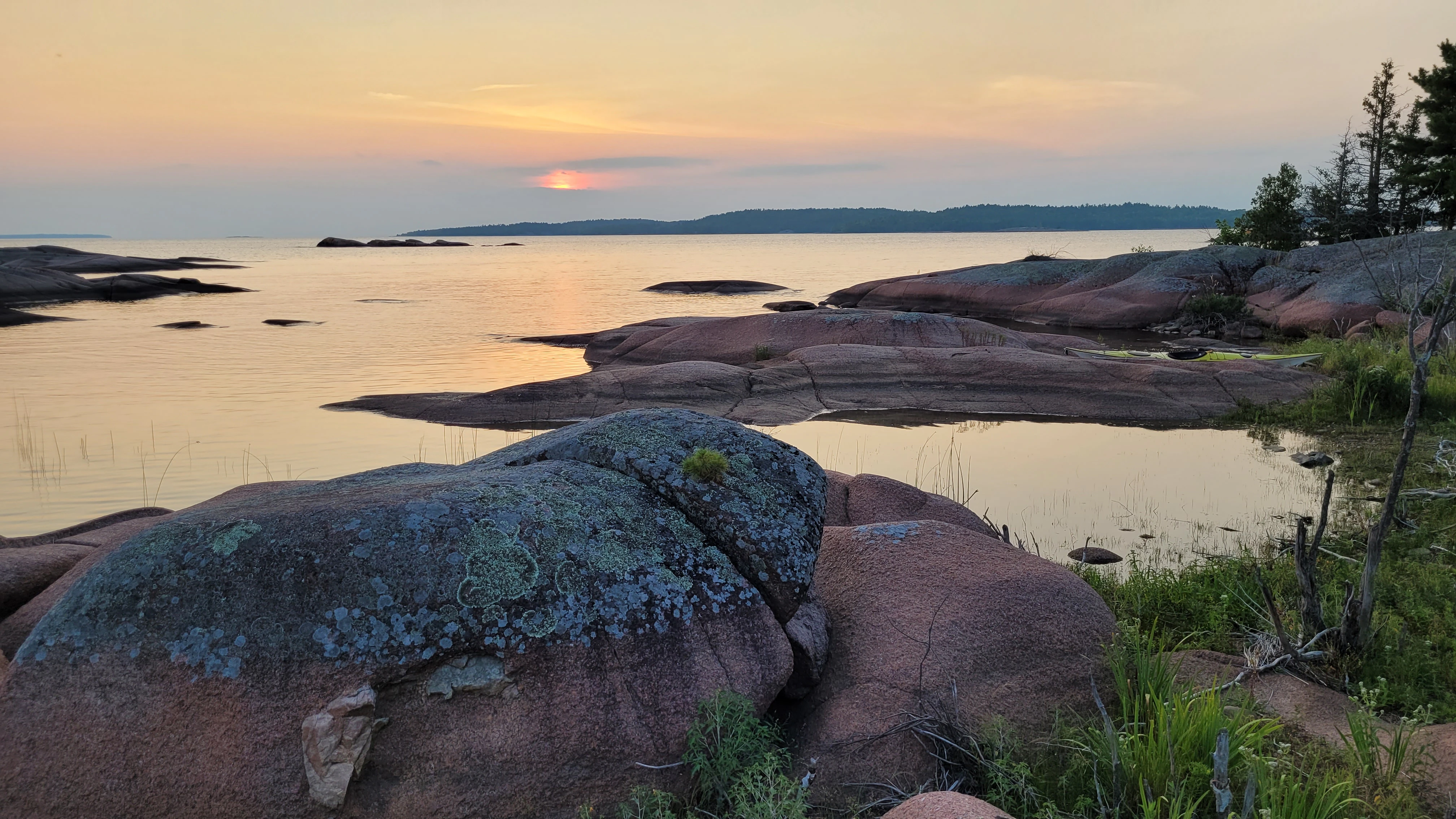A sunset over smooth red granite rocks during a kayak trip to the Benjamin Islands in Northern Ontrario, Canada
