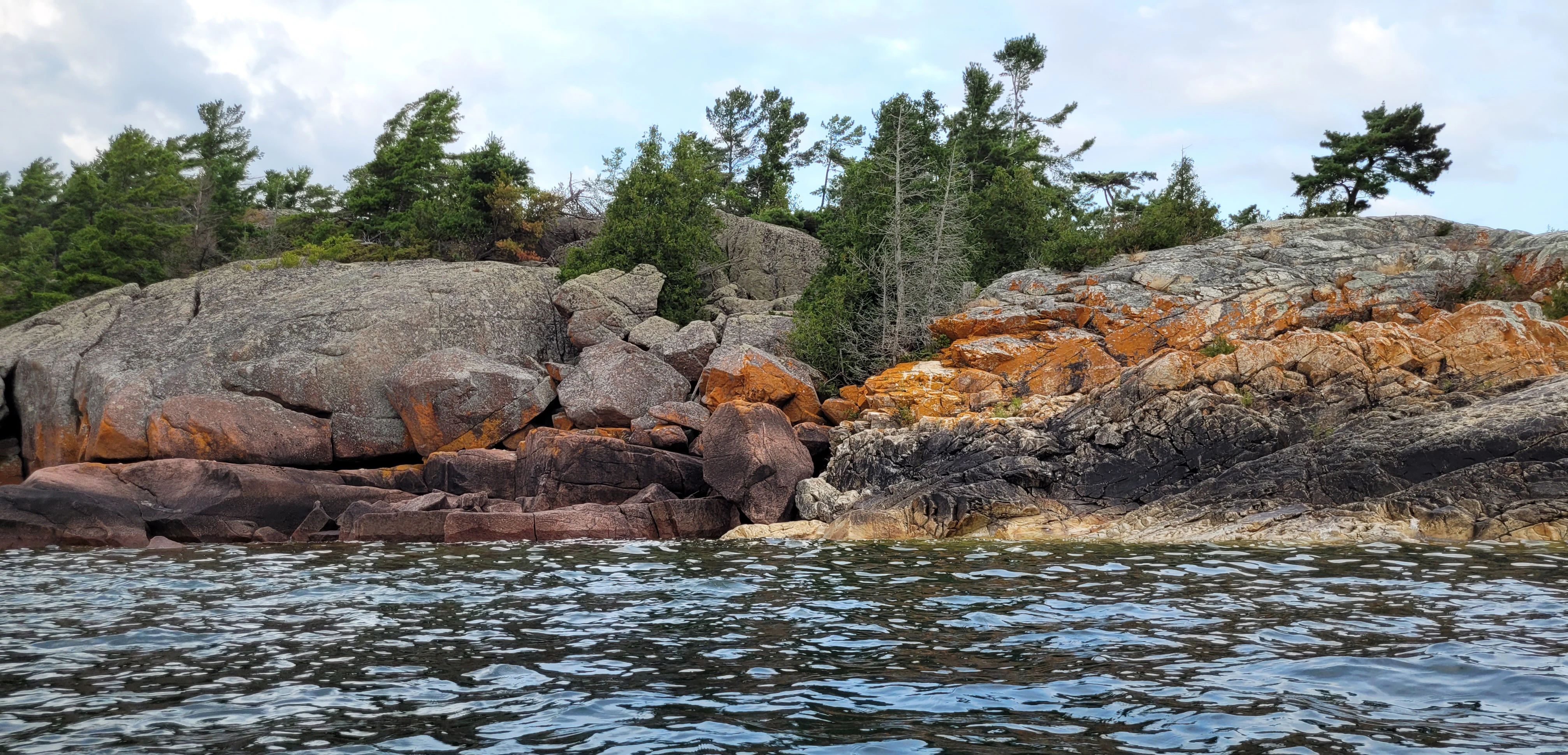 Red granite rocks and white quartzite with orange lichen on the Benjamin Islands in Northern Ontrario, Canada