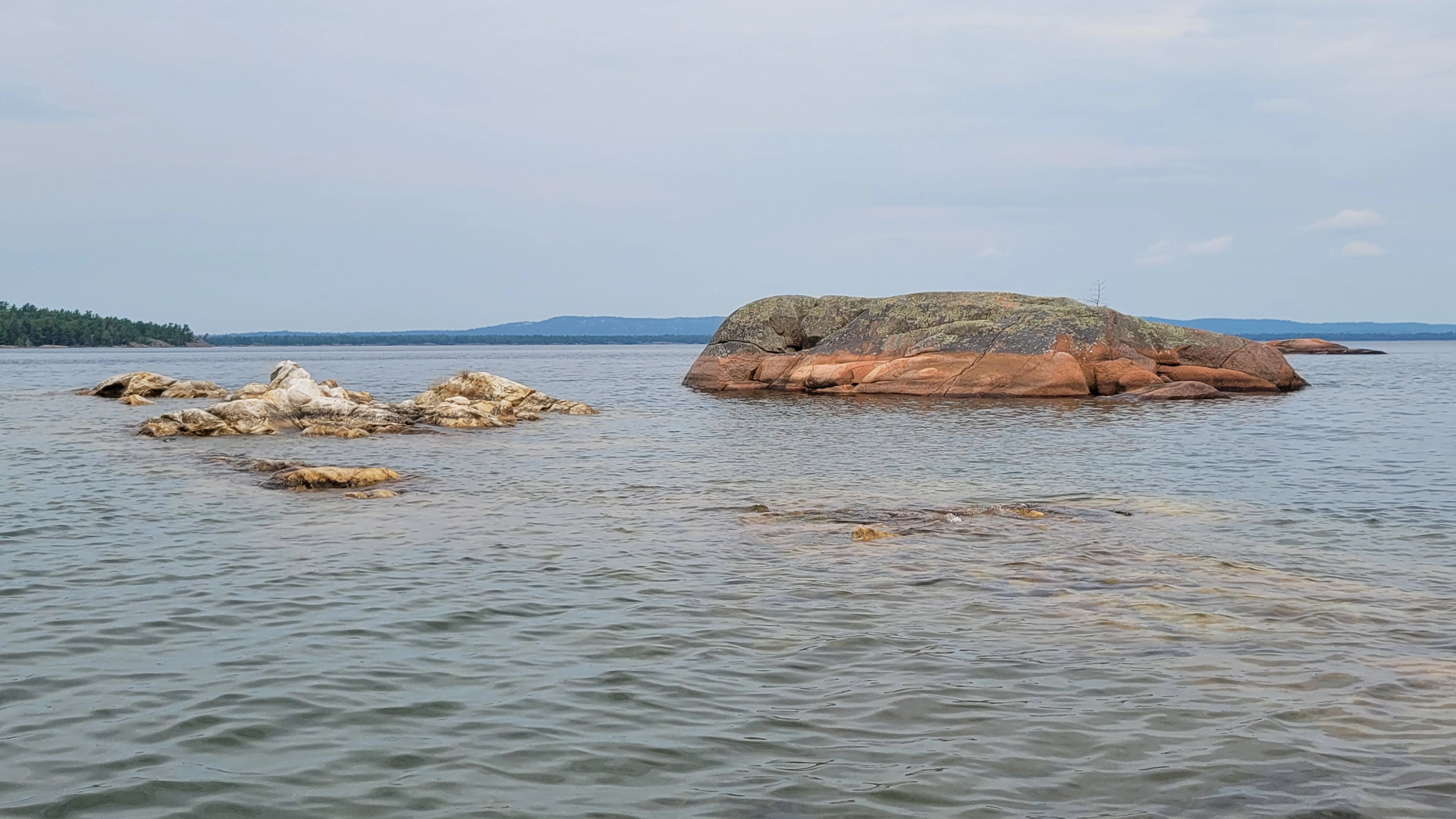 Kayaking passed smooth granite cliffs meeting white quartzite cliffs on South Benjamin Island in Northern Ontrario, Canada