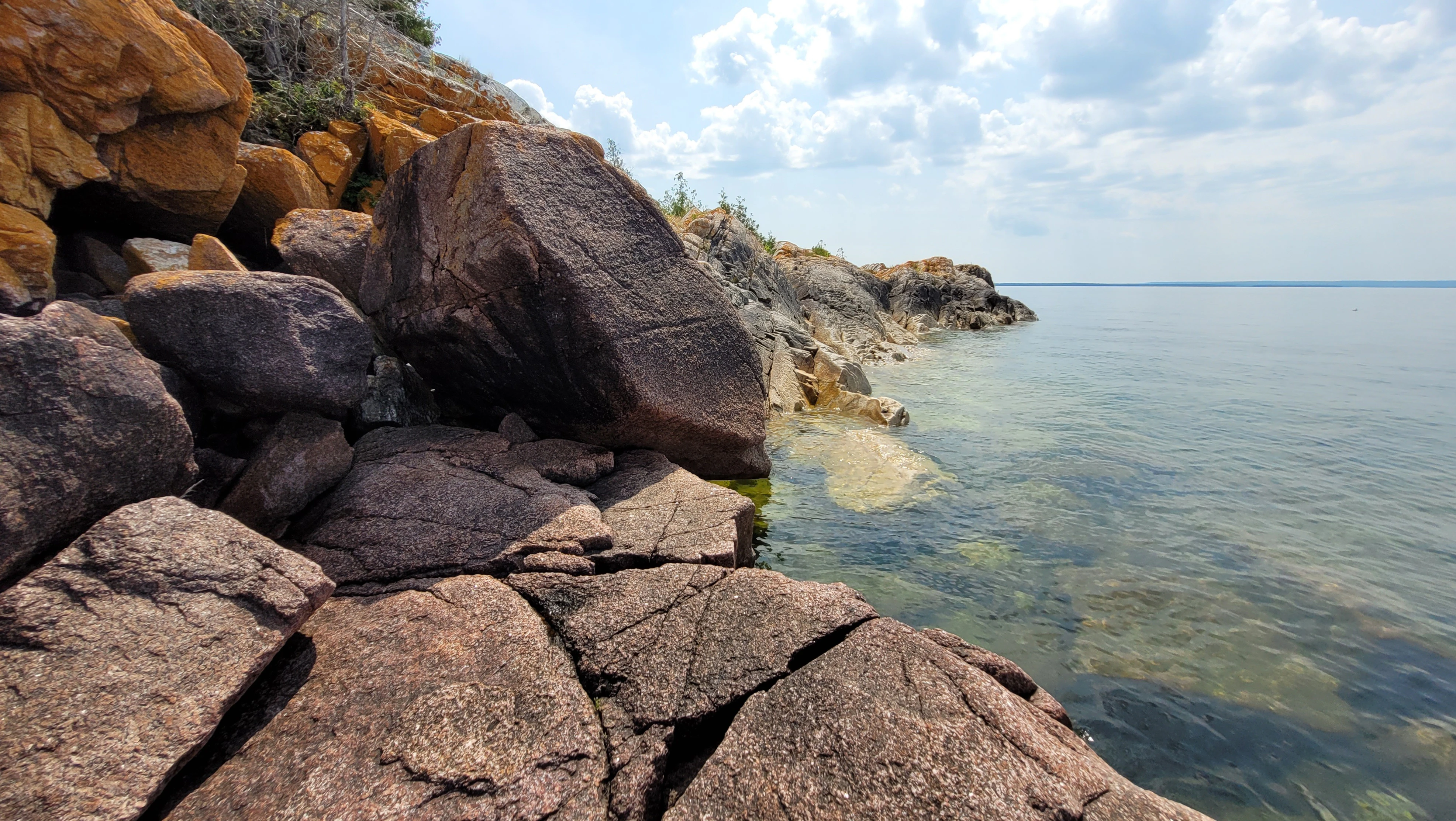 Western Shoreline of the Benjamind islands with red granite rock, white quartzite,
                trees and clear water