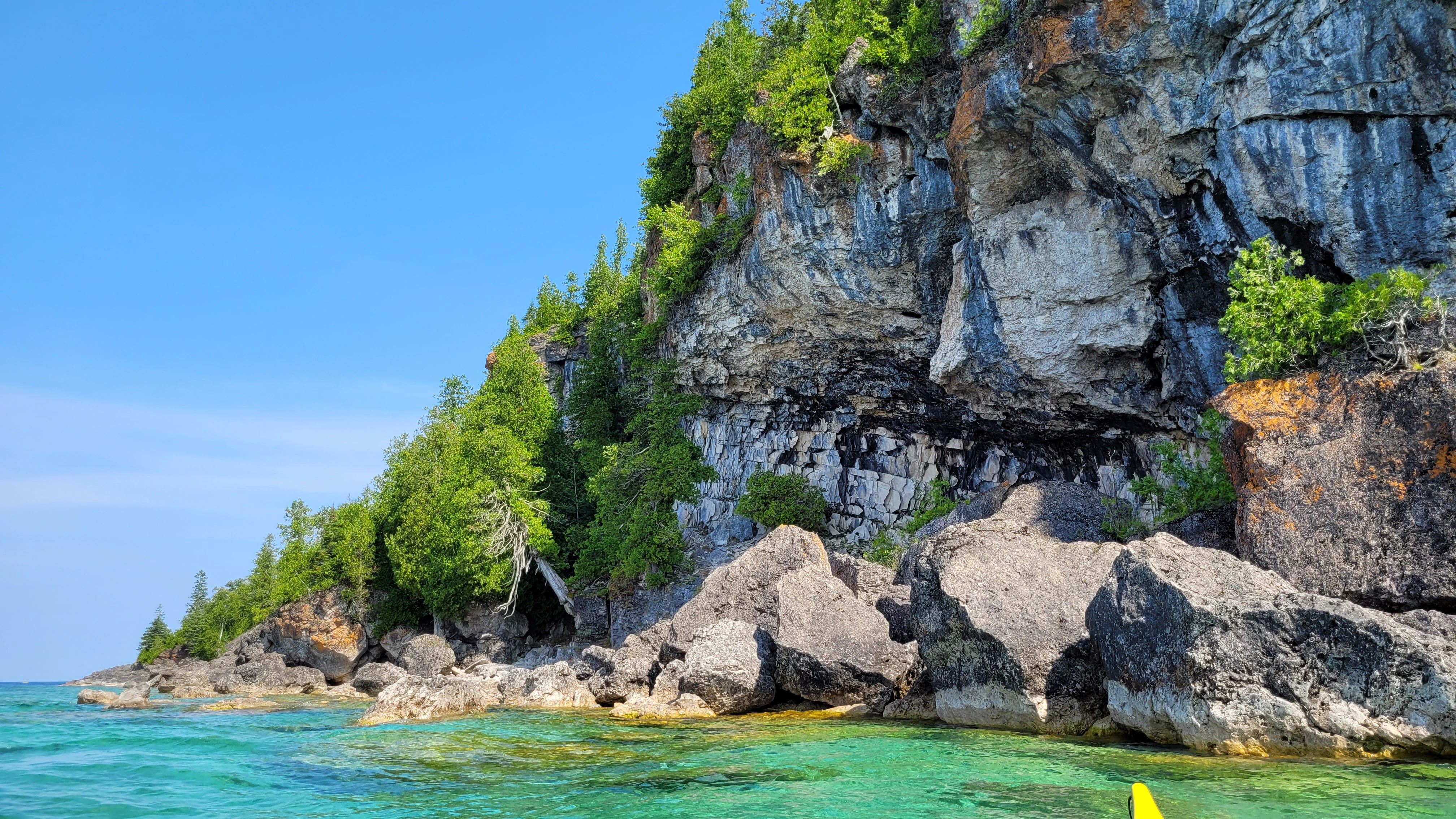 Opposite side of Driftwood Cove showing layered limestone cliffs