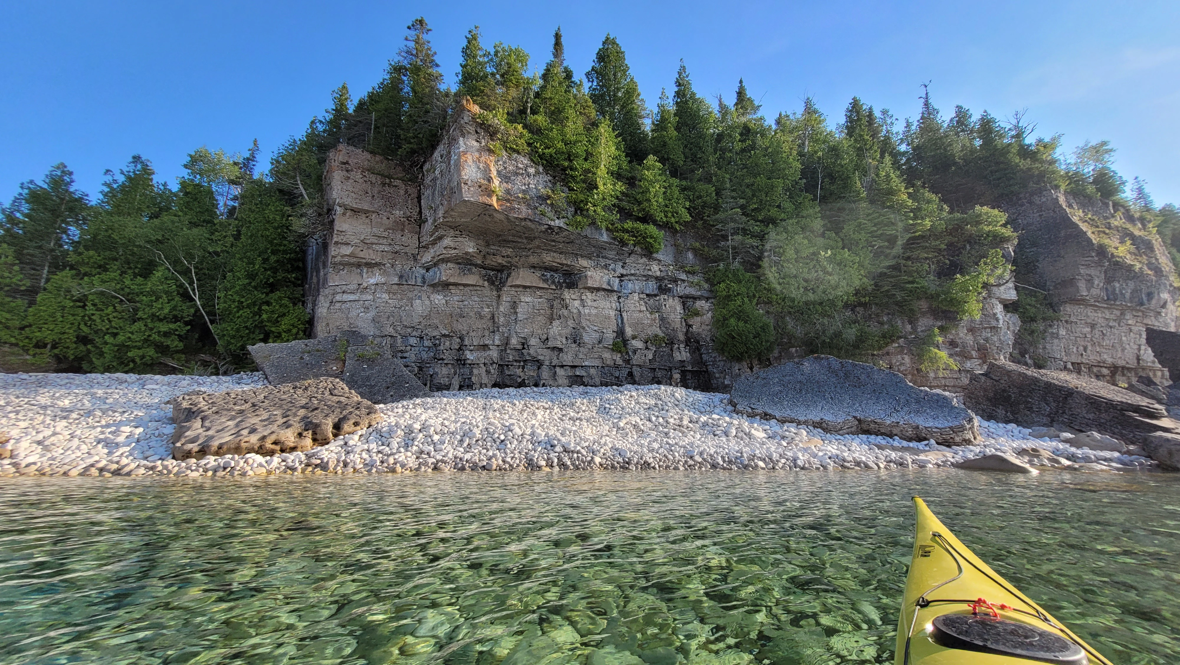Rocky shoreline beneath towering escarpment cliffs in Driftwood Cove