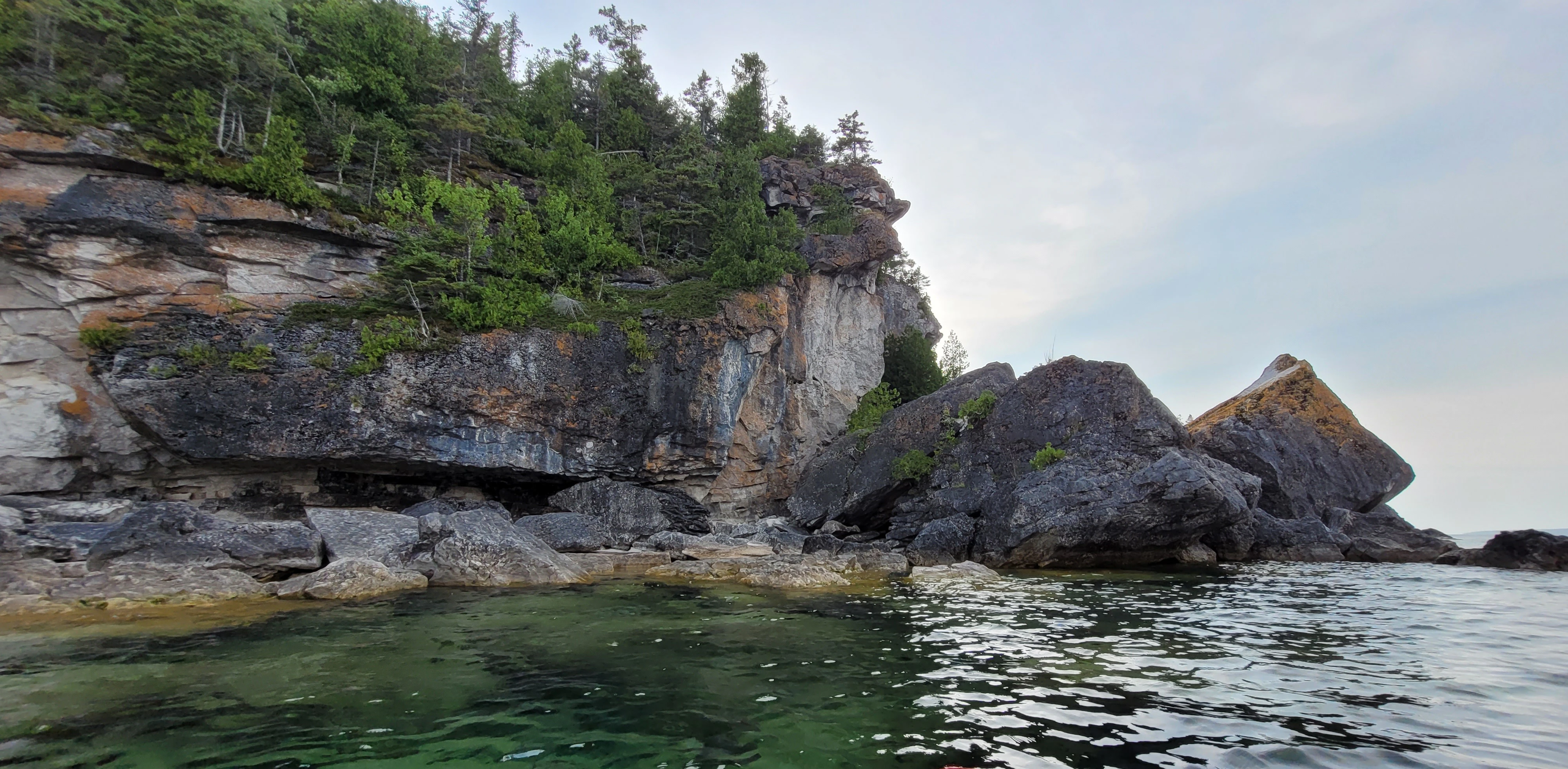 Colorful cliff face and shoreline boulder along the Bruce Peninsula