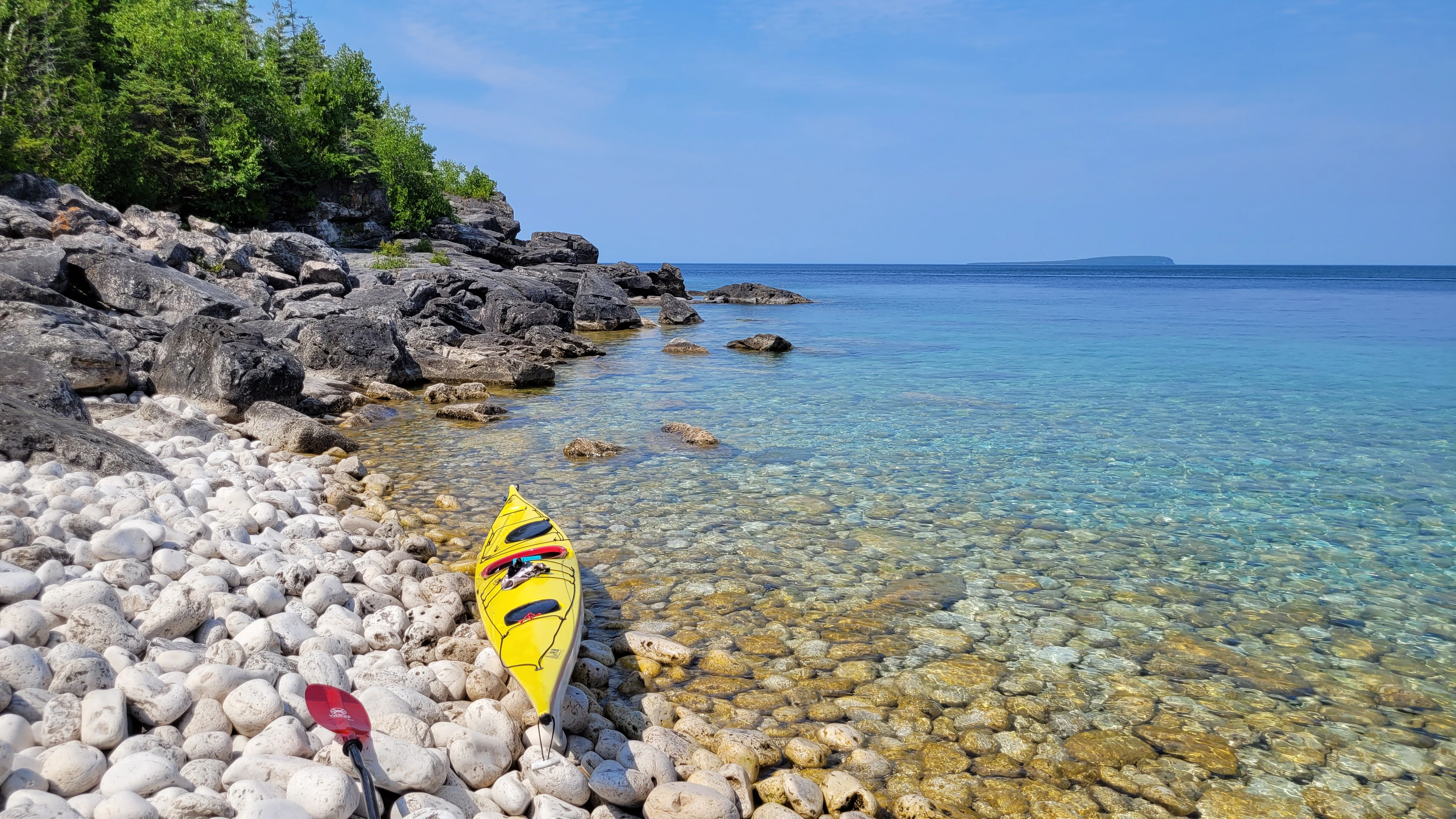 Sea kayak resting on a cobblestone beach along the Bruce Peninsula