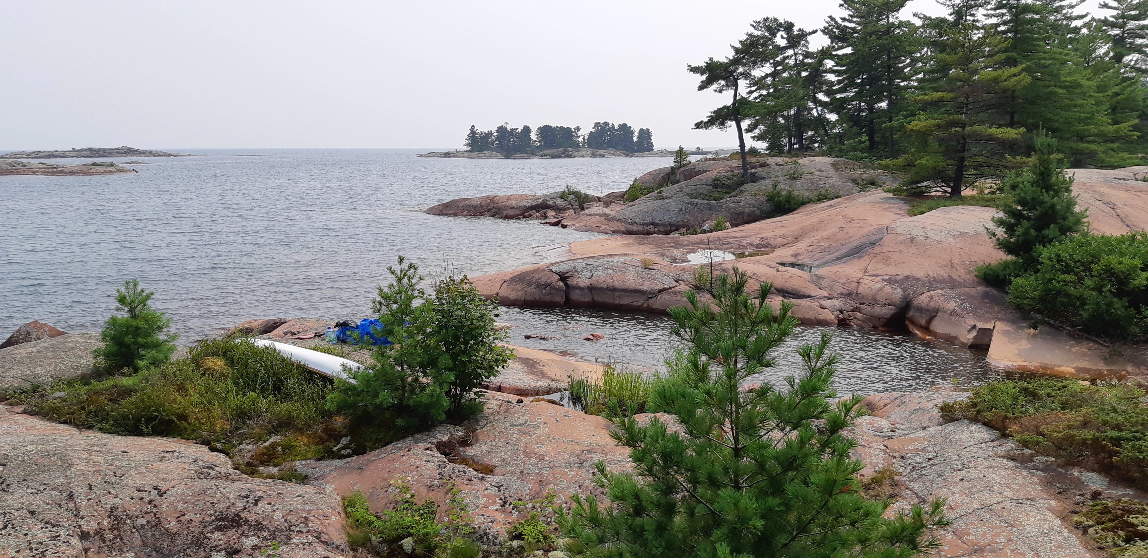 George Island across from Killarney, Ontario, with a sea kayak next to a rock and the La Cloche Mountains far in the distance